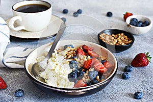 Breakfast - cottage cheese with berries and a cup of coffee, top view. Granola with nuts, honey and strawberries