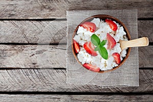 breakfast cottage cheese with strawberry in bowl on wooden background top view