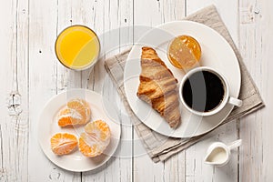 Breakfast with croissant, coffee jam, orange juice and mandarin