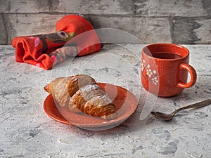 Breakfast with croissant and tea in an orange mug with a pattern