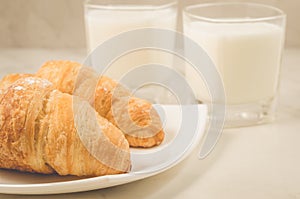 breakfast with croissants and milk/croissants in a plate and glasses milk on a white table. Selective focus