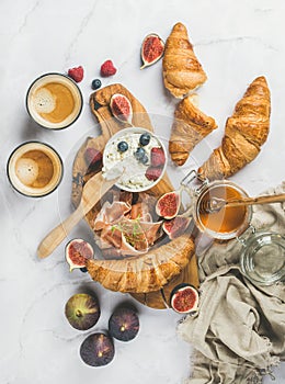 Breakfast with croissants, ricotta, coffee and berries over marble background