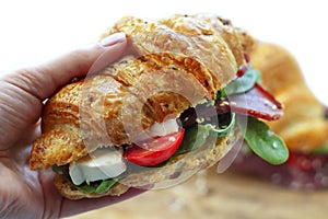 Breakfast croissants sandwich with meat, cheese, tomatos, avocado and green spinah isolated on white background.