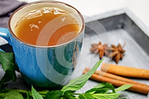 Breakfast. A cup of tea on a tray with a bunch of mint, starlets of anise and chopsticks of cinnamon