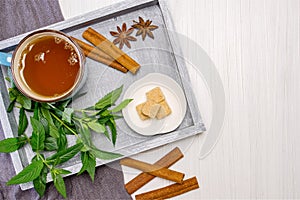 Breakfast. A cup of tea on a tray with a bunch of mint, starlets of anise and chopsticks of cinnamon