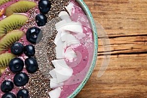 Breakfast with delicious acai smoothie and healthy ingredients in bowl on wooden table, top view. Space for text