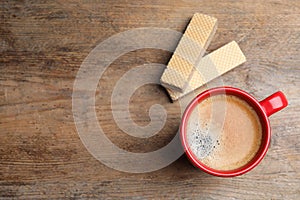 Breakfast with delicious wafers and coffee on wooden table, flat lay. Space for text