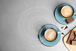 Breakfast with delicious wafers and cups of coffee on table, flat lay. Space for text