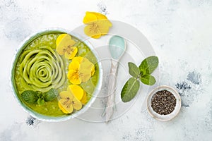 Breakfast detox green smoothie bowl topped with kiwi rose and edible Pansy flowers.