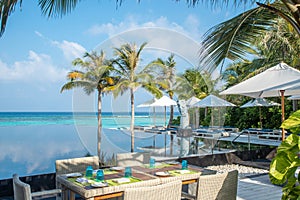 Breakfast dining set up white chairs and table near swimming pool at the tropical outdoor restaurant at island luxury resort
