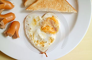 Breakfast dish of heart shaped fried egg, sausages and toasts