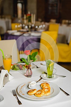 Breakfast in empty restaurant. Ð¡ottage cheese pancakes or syrniki on the table.