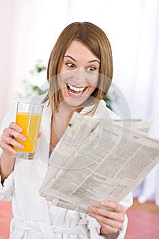 Breakfast - excited woman reading newspaper