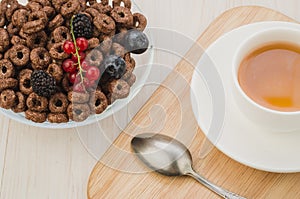 Breakfast with flakes, berries and a cup of tea. Top view/breakfast with flakes, berries, spoon and a cup of tea. Top view