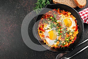 Breakfast food concept. Shakshuka with eggs, tomato, and dill in iron pan. Top view, copy space