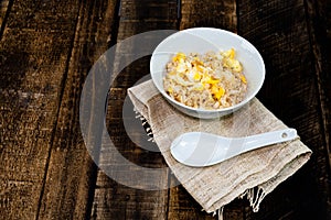 Breakfast food fried rice with egg in bowl have spoon on wood table.