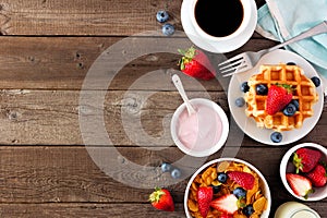 Breakfast food side border. Fruits, cereal, waffles, yogurt and coffee. Top view over wood with copy space.