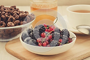 Breakfast with fresh berries, flakes, honey and a cup of tea/breakfast with fresh berries, flakes, honey and a cup of tea.