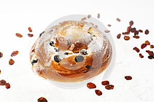 Breakfast. Fresh sweet bun with powdered sugar and raisins on white background