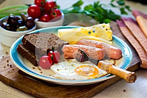 Breakfast with fried egg, sausages, bread, tomato, cheese