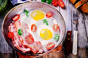 Breakfast with fried eggs, bacon, tomatoes and parsley