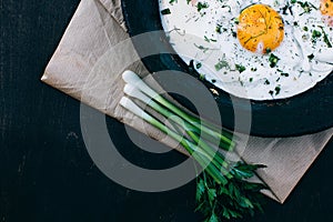 Breakfast. Fried eggs in cast iron frying pan on dark wooden background