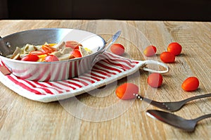 Breakfast with fried eggs in a pan with white pork sausage, tomato, fork on a wooden background