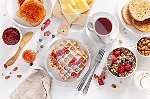 Breakfast with granola berry nuts, waffle, toast, jam, chocolate spread and coffee. Top view