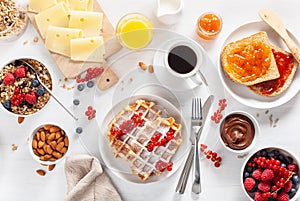 Breakfast with granola berry nuts, waffle, toast, jam, chocolate spread and coffee. Top view