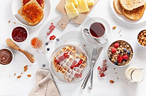 Breakfast with granola berry nuts, waffle, toast, jam, chocolate spread and coffee. Top view