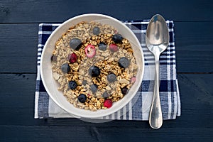 Breakfast granola cereal bowl with fruit and berries and spoon