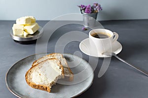 Breakfast of homemade carrot bread, butter and a cup of espresso on a gray background.