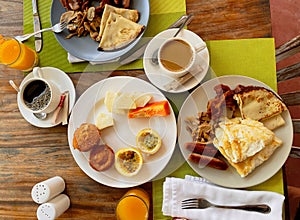 Breakfast in the hotel restaurant on the table with scrambled eggs, bacon, pancakes, sausages, mushrooms, coffee, juice and fruit