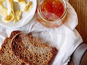 Breakfast with integral toast, butter and apricot jam on wooden table