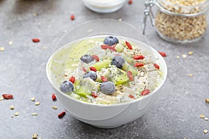 Breakfast kiwi smoothie bowl with oat flakes and berries. Tasty kiwi smoothie with banana, Goji berries, blueberries, Chia seeds