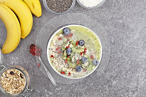 Breakfast kiwi smoothie bowl with oat flakes and berries. Tasty kiwi smoothie with banana, Goji berries, blueberries, Chia seeds