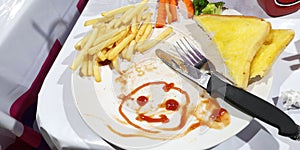 Breakfast or lunch the boy create to drawn tomato sauce cartoon smiling face on his plate white color