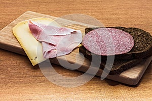 Breakfast or lunch setting with ham cheese an brown sandwich bread on wooden board