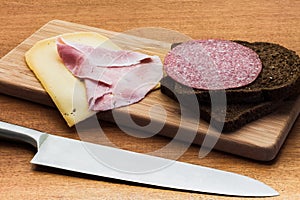 Breakfast or lunch setting with ham cheese an brown sandwich bread on wooden board