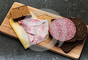 Breakfast or lunch setting with ham cheese an brown sandwich bread on wooden board