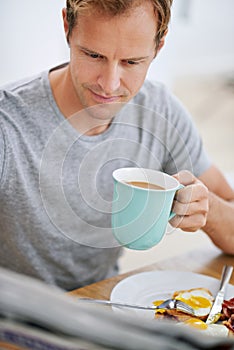 Breakfast, man and newspaper in morning for news, articles and reports before work. Male person, coffee and tabloid at photo