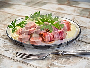 Breakfast with mashed potatoes, bacon and sausages, parsley sprigs, on a light table