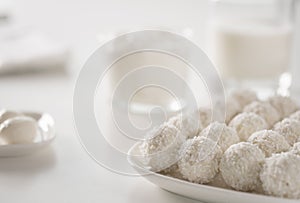 Breakfast - milk, eggs, cream cheese and raffaello coconut confectionery on white wood table. white on white picture.