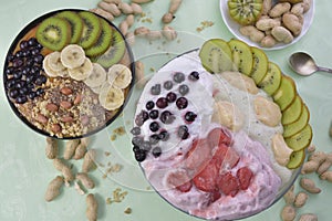 Breakfast with muesli, acai blueberry smoothie and kiwi, fruits on green background. Healthy food concept. Flat lay, top vie