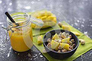 Breakfast of muesli with fresh mango pieces and cashew nuts with smoothie