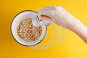 Healthy breakfast. A young woman is pouring cereals with milk