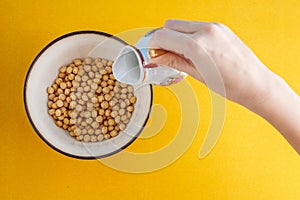 Healthy breakfast. A young woman is pouring cereals with milk