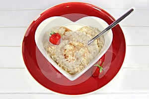 Breakfast of Oatmeal or Porridge in a heart bowl with strawberry