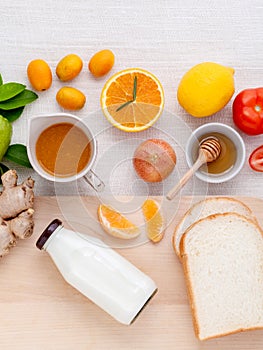 Breakfast with orange juice, oranges, oranges slice, passion fruit , ginger,tomato and Kiwi set up on wooden table .