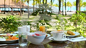 Breakfast in outdoors restaurant at luxury exotic resort with sea and palm trees